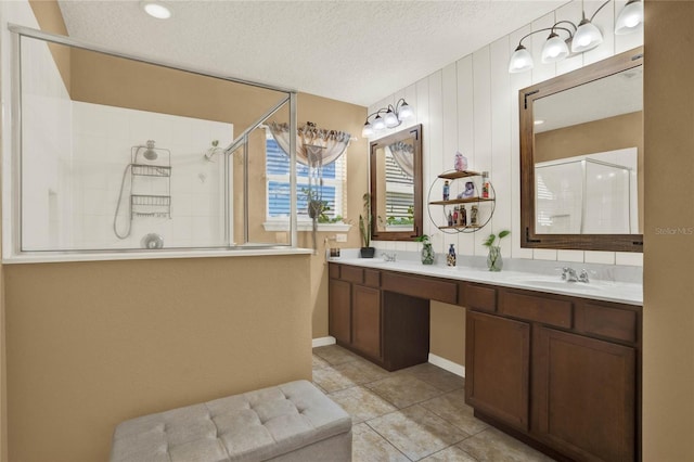 full bathroom with double vanity, a sink, a textured ceiling, tile patterned flooring, and tiled shower