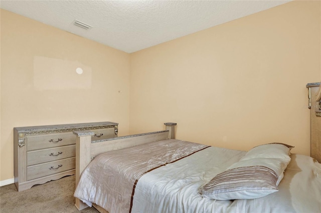 bedroom featuring a textured ceiling, baseboards, visible vents, and light colored carpet