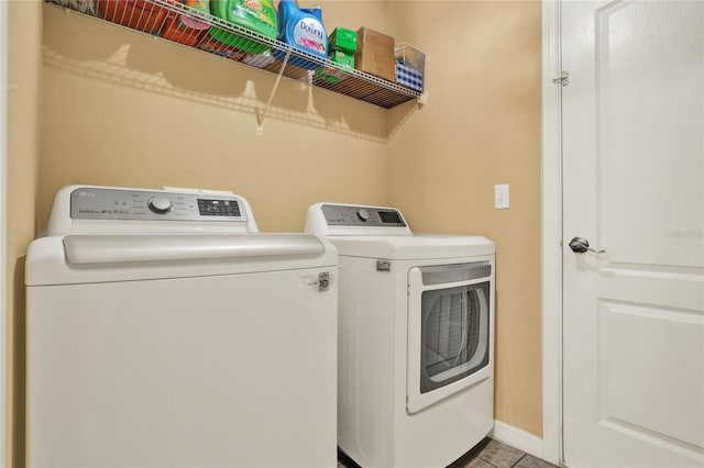 laundry area featuring tile patterned floors, laundry area, baseboards, and separate washer and dryer