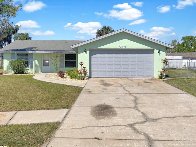 ranch-style home with driveway, an attached garage, fence, a front lawn, and stucco siding