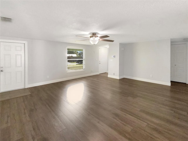 empty room with baseboards, visible vents, and dark wood-style flooring