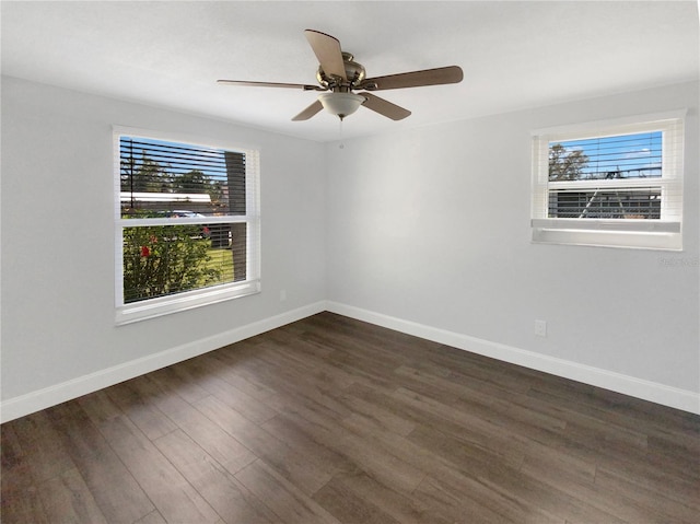 empty room featuring dark wood-style flooring, a ceiling fan, and baseboards