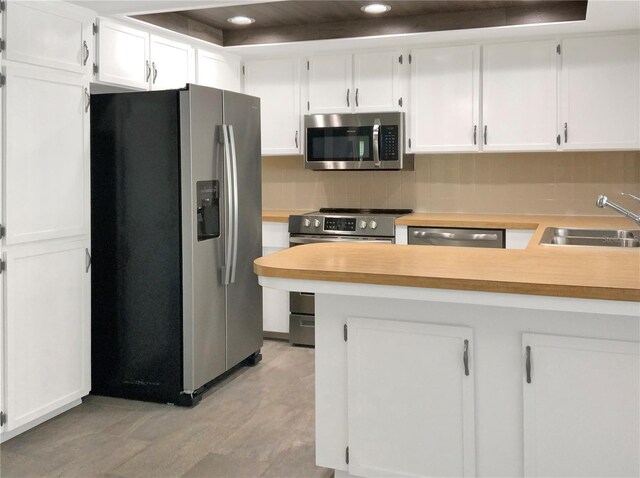 kitchen with stainless steel appliances, tasteful backsplash, light countertops, white cabinetry, and a sink