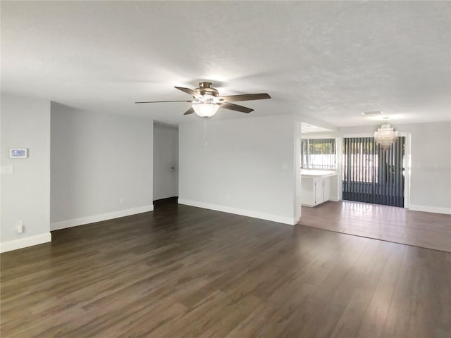 empty room with dark wood-type flooring, baseboards, and ceiling fan with notable chandelier