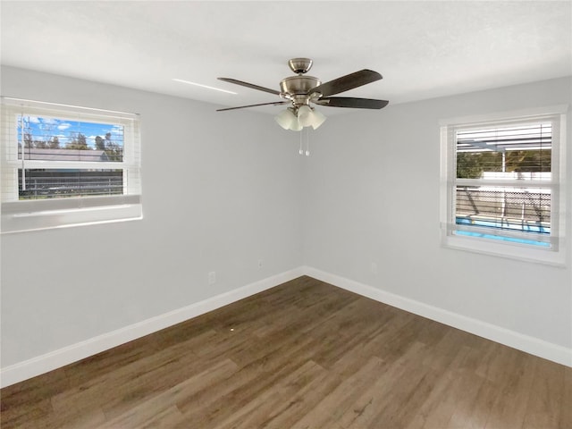 empty room featuring dark wood finished floors, baseboards, and ceiling fan