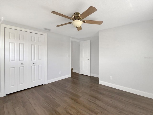 unfurnished bedroom with dark wood-style floors, a closet, visible vents, and baseboards