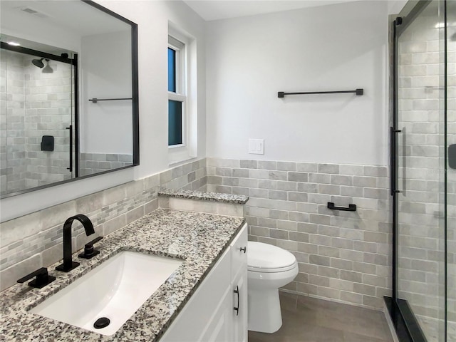 full bathroom featuring a wainscoted wall, tile walls, toilet, a stall shower, and vanity