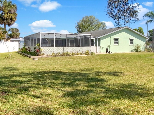 back of house with a lawn, fence, a sunroom, and stucco siding