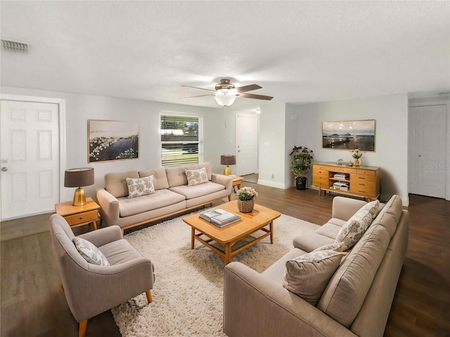 living area featuring a ceiling fan, visible vents, baseboards, and wood finished floors