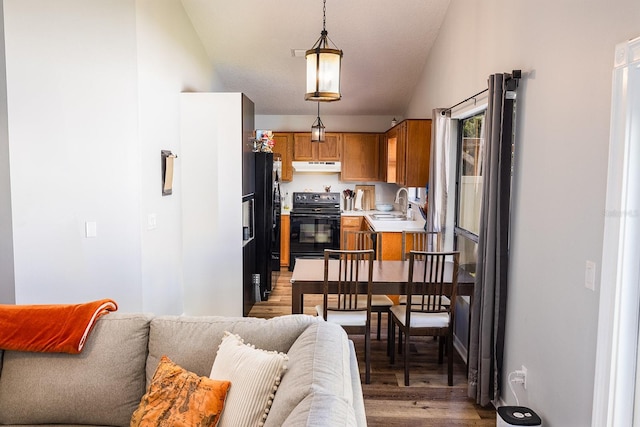 kitchen featuring under cabinet range hood, a sink, open floor plan, light countertops, and range