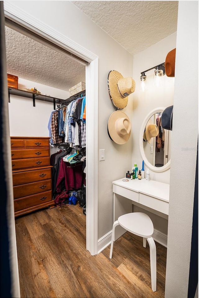 bathroom with a textured ceiling, baseboards, and wood finished floors