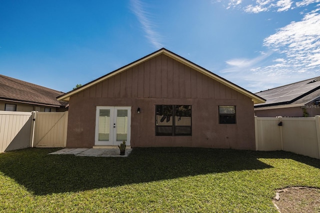 rear view of house featuring french doors, a lawn, a fenced backyard, and a gate