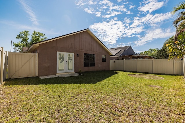 rear view of property featuring a lawn, a fenced backyard, and a gate