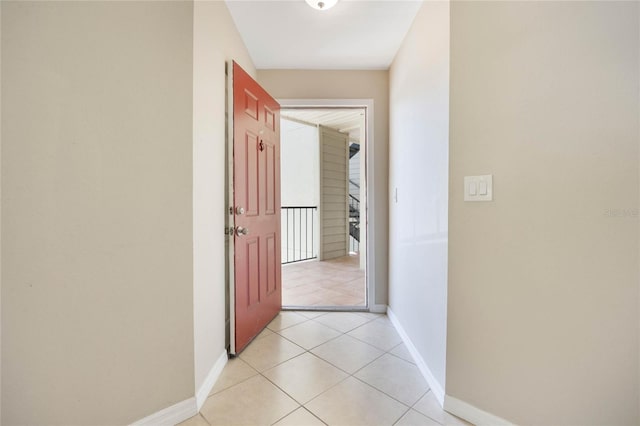 corridor featuring baseboards and light tile patterned flooring