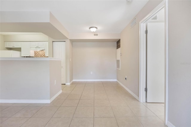 hall with baseboards, visible vents, and light tile patterned flooring