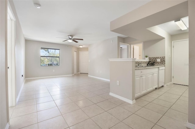 interior space with light tile patterned floors, baseboards, and a ceiling fan