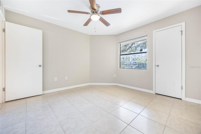 unfurnished room featuring light tile patterned floors, a ceiling fan, and baseboards