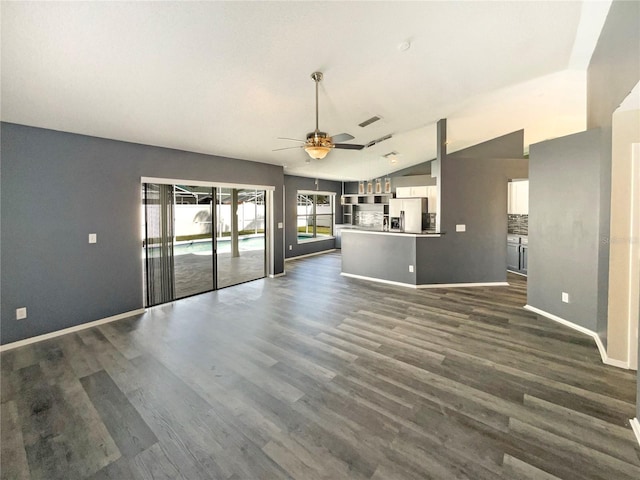 unfurnished living room with lofted ceiling, ceiling fan, dark wood-type flooring, and baseboards