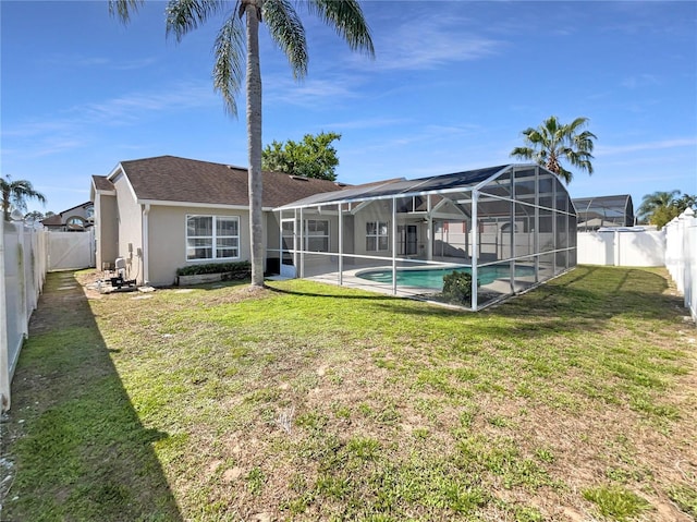 back of house featuring glass enclosure, a yard, a fenced backyard, and stucco siding