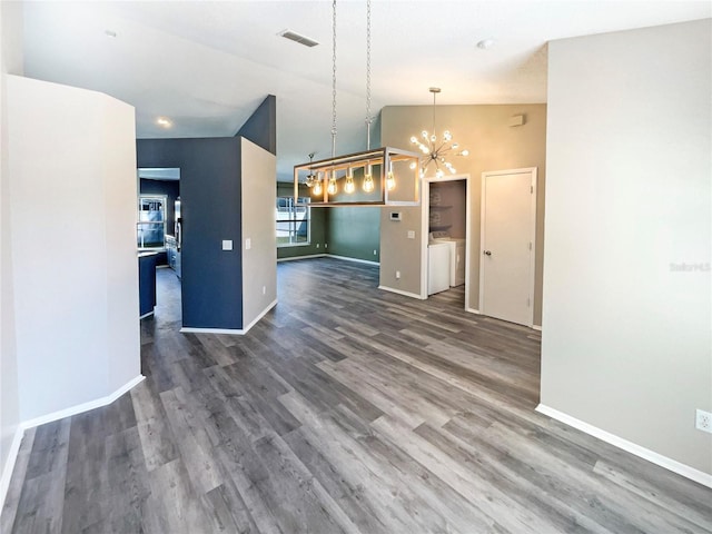 kitchen featuring a notable chandelier, washing machine and clothes dryer, lofted ceiling, visible vents, and wood finished floors