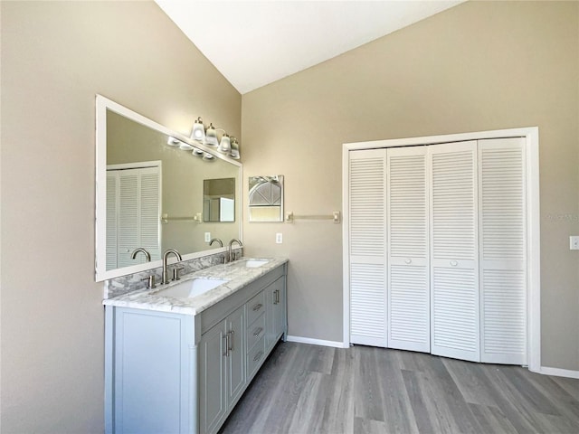 bathroom with vaulted ceiling, double vanity, a sink, and wood finished floors