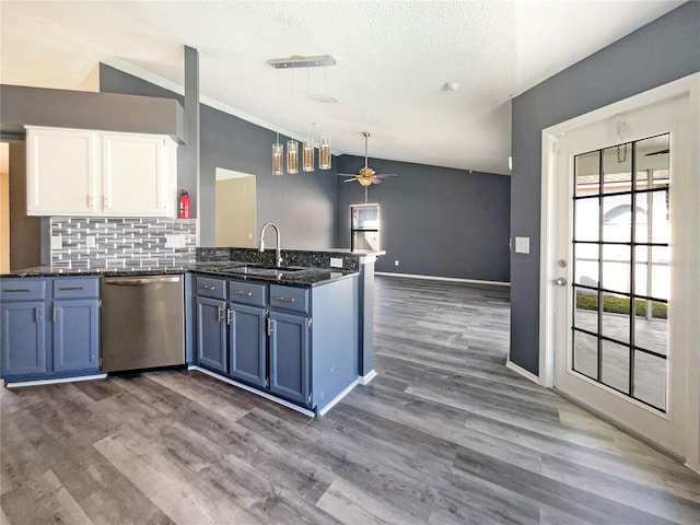 kitchen featuring stainless steel dishwasher, white cabinetry, vaulted ceiling, blue cabinets, and a peninsula