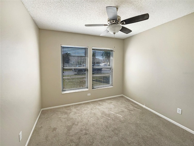 carpeted spare room featuring a textured ceiling, a ceiling fan, and baseboards