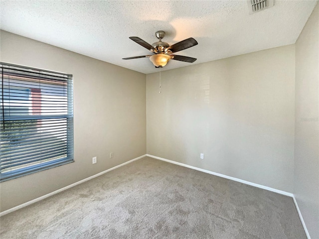 spare room featuring ceiling fan, carpet floors, visible vents, and baseboards