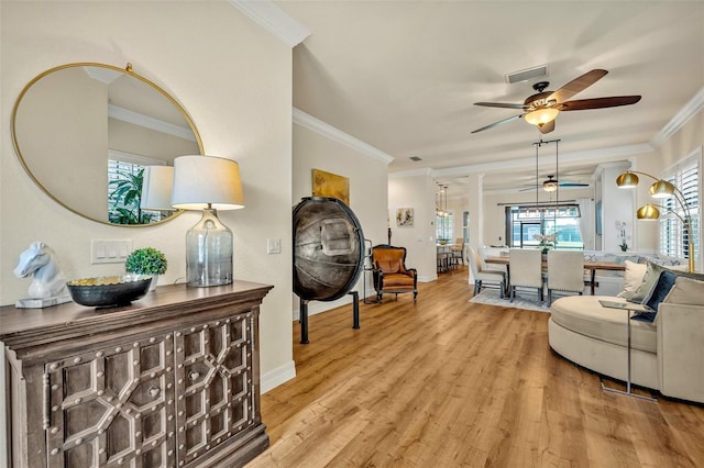 living room featuring light wood-style floors, baseboards, and ornamental molding