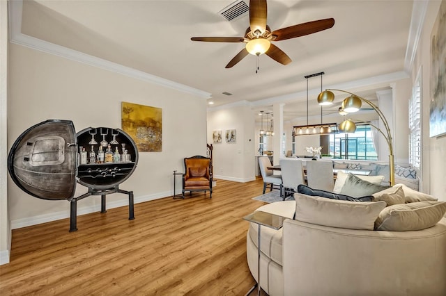 living room featuring crown molding, light wood-style floors, baseboards, and visible vents