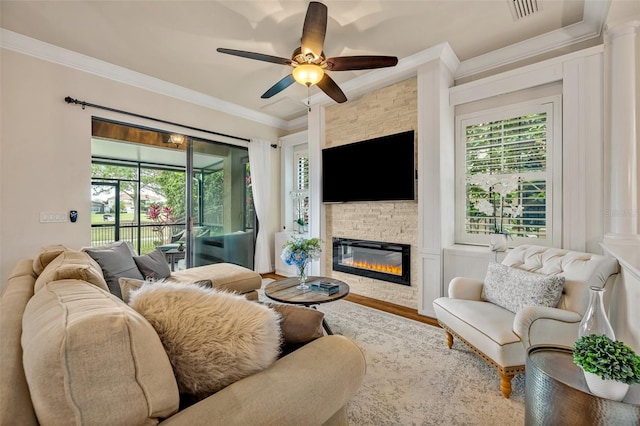 living room featuring crown molding, a fireplace, visible vents, and a wealth of natural light