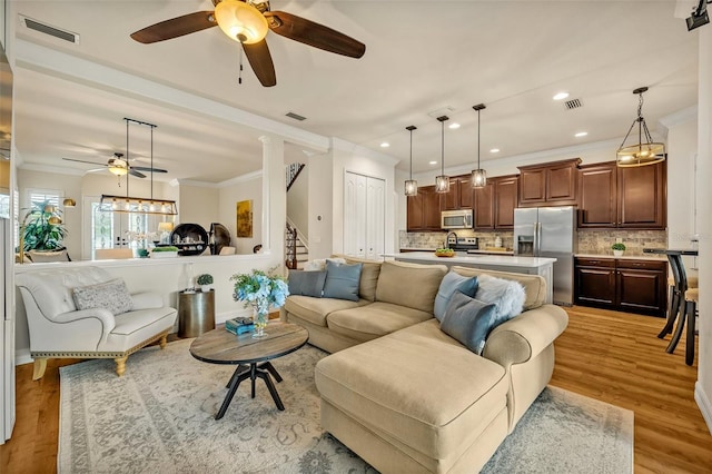 living area featuring crown molding, visible vents, and light wood-type flooring