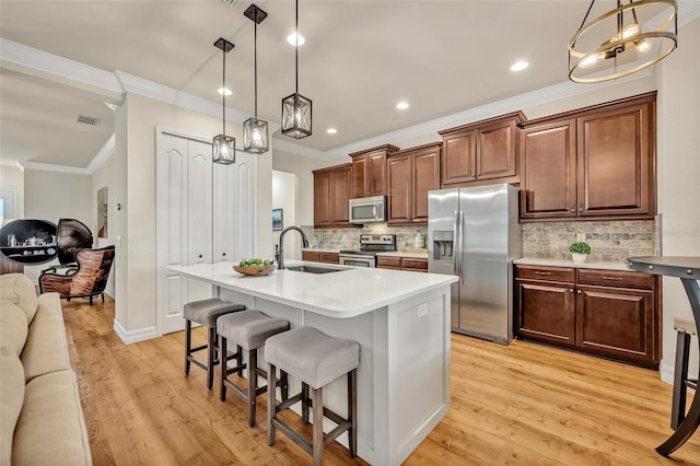 kitchen with visible vents, open floor plan, light wood-style flooring, appliances with stainless steel finishes, and a sink