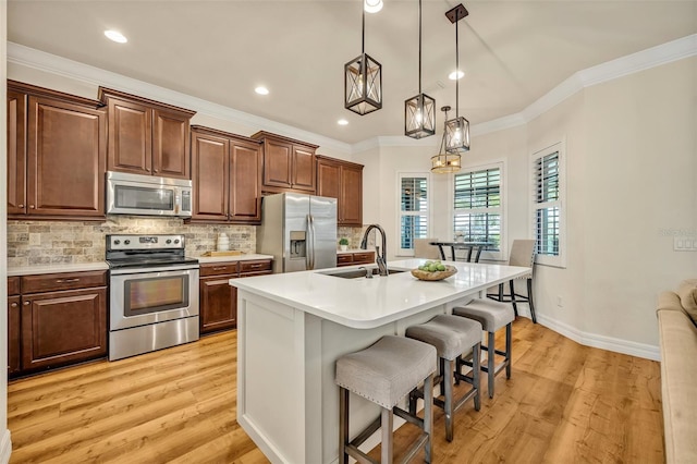 kitchen featuring a kitchen bar, a sink, tasteful backsplash, stainless steel appliances, and light countertops