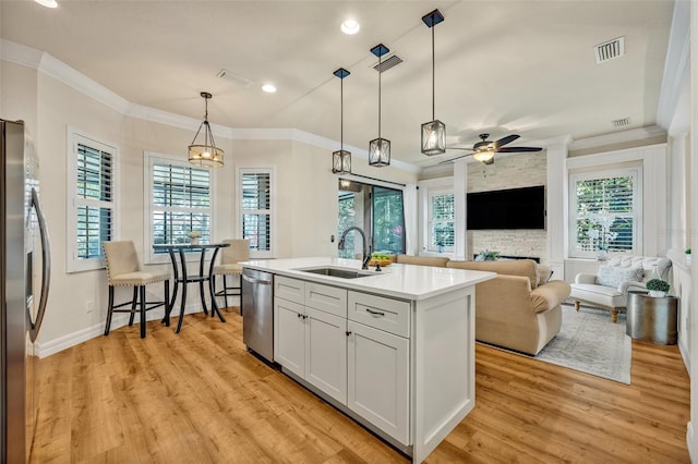 kitchen with visible vents, a sink, light wood-style floors, appliances with stainless steel finishes, and crown molding