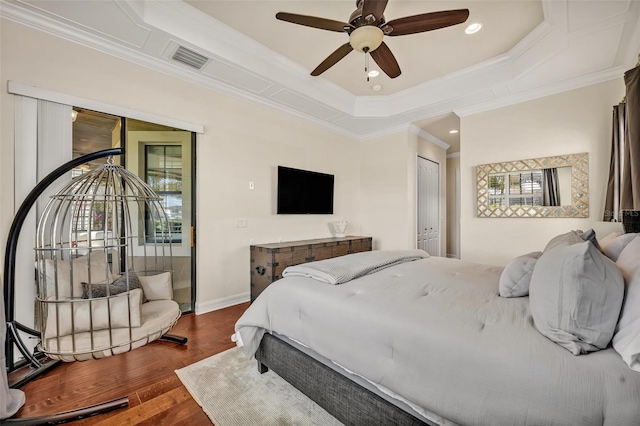 bedroom featuring visible vents, crown molding, baseboards, a tray ceiling, and wood finished floors