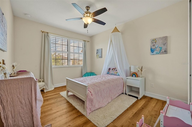 bedroom with light wood finished floors, a ceiling fan, and baseboards