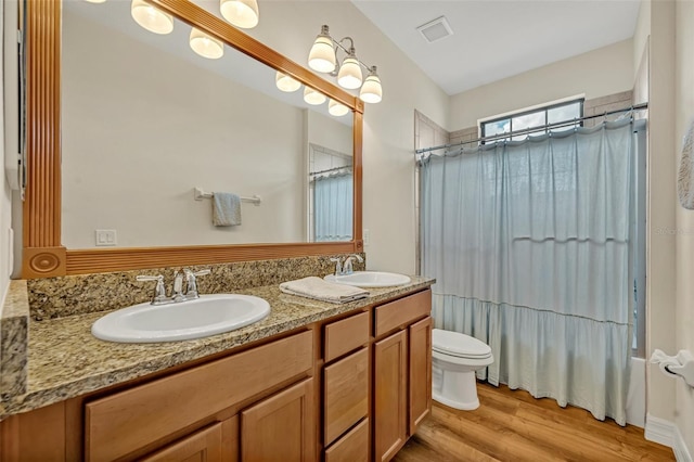 full bath with a sink, visible vents, toilet, and wood finished floors