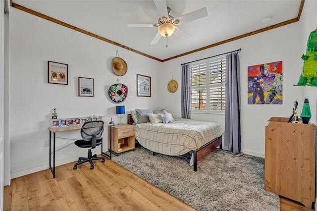 bedroom featuring light wood finished floors, ceiling fan, baseboards, and ornamental molding