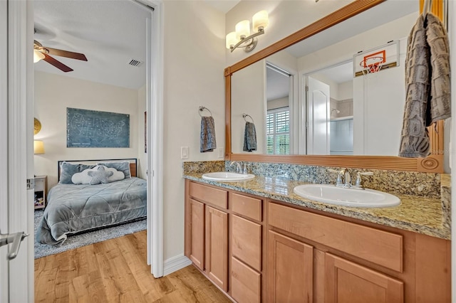 ensuite bathroom featuring ensuite bath, wood finished floors, visible vents, and a sink