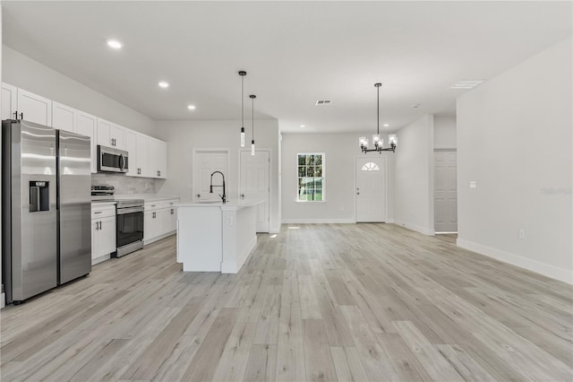 kitchen with decorative backsplash, appliances with stainless steel finishes, light wood-style floors, white cabinetry, and a sink