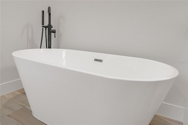 details with a freestanding bath and wood finished floors