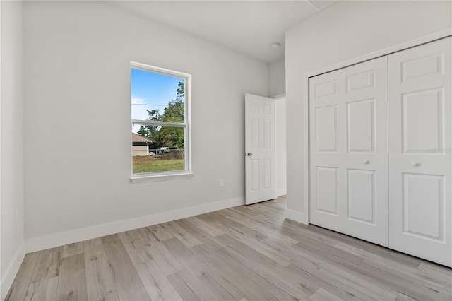 unfurnished bedroom with light wood-style flooring, baseboards, and a closet