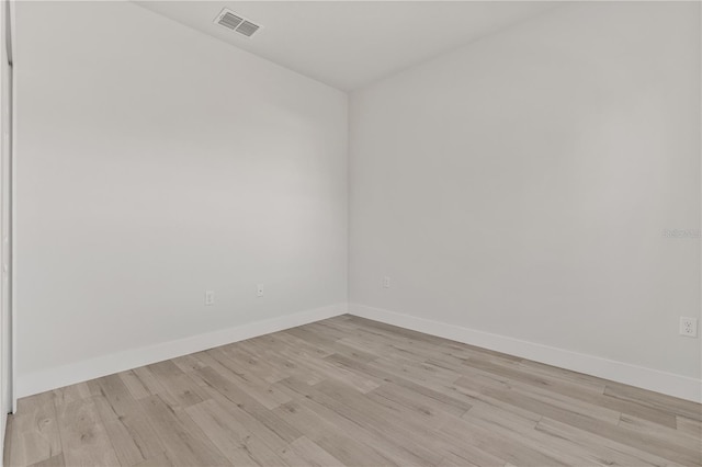 unfurnished room with light wood-type flooring, visible vents, and baseboards