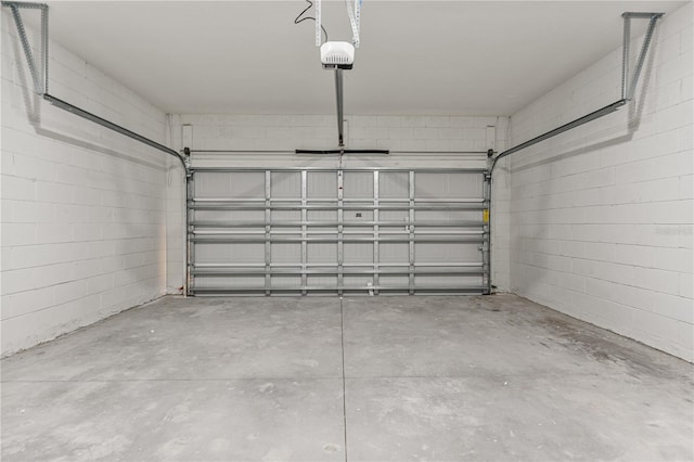 garage with a garage door opener and concrete block wall