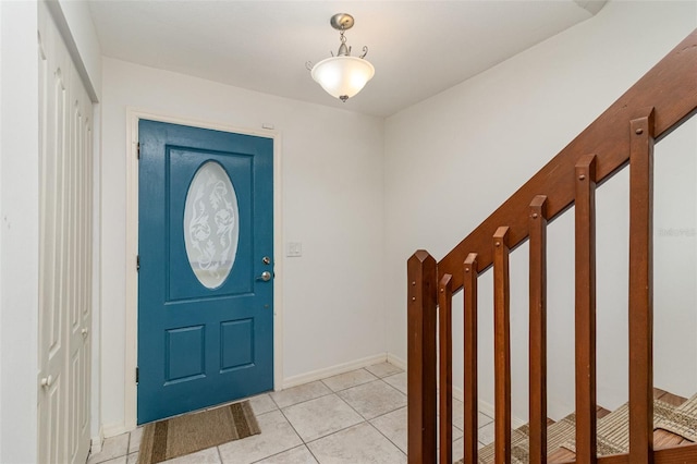 entrance foyer with light tile patterned flooring, baseboards, and stairs