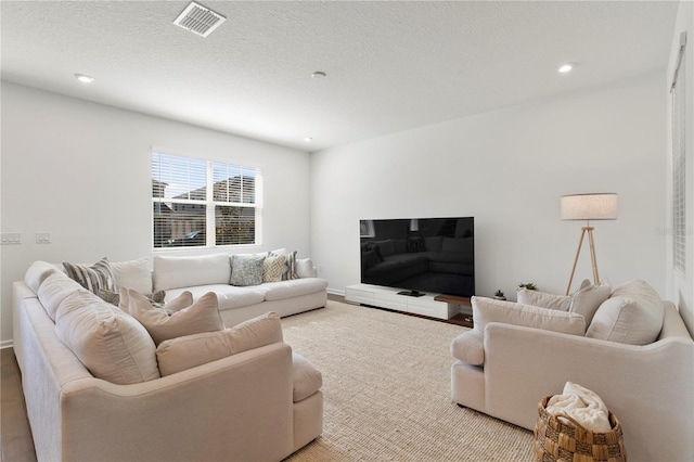 living area with visible vents, recessed lighting, and a textured ceiling