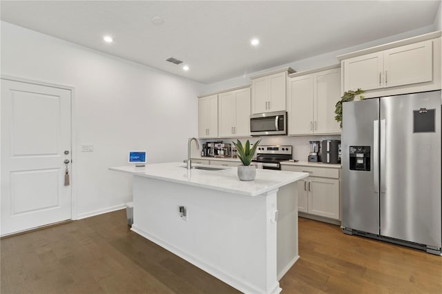 kitchen featuring tasteful backsplash, a sink, dark wood-style floors, stainless steel appliances, and a kitchen island with sink