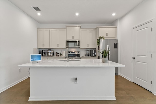 kitchen with visible vents, a center island with sink, a sink, backsplash, and appliances with stainless steel finishes