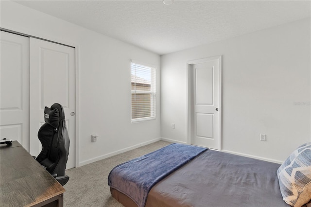 carpeted bedroom with a closet, baseboards, and a textured ceiling